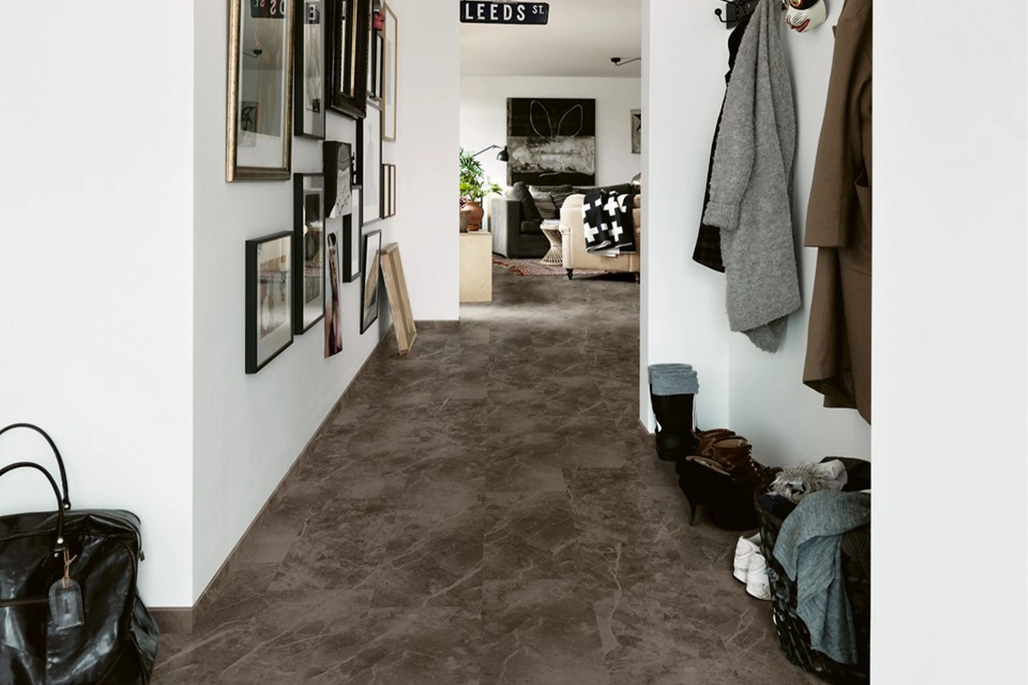 Przedpokój z ciemną podłogą laminowaną i galerią obrazów na ścianie